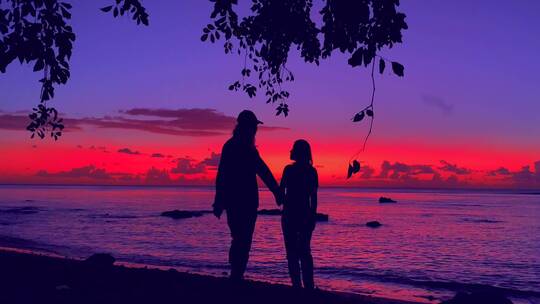 夕阳余晖下情侣牵手散步在沙滩