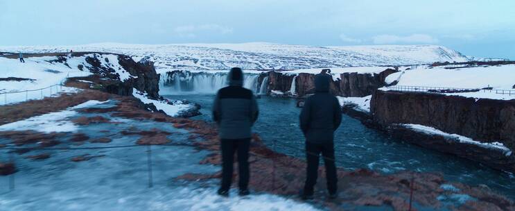 两个男人站在岸边欣赏冰川瀑布景观