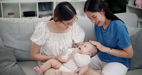 两个年轻的亚洲女人在家里开心地和一个婴儿