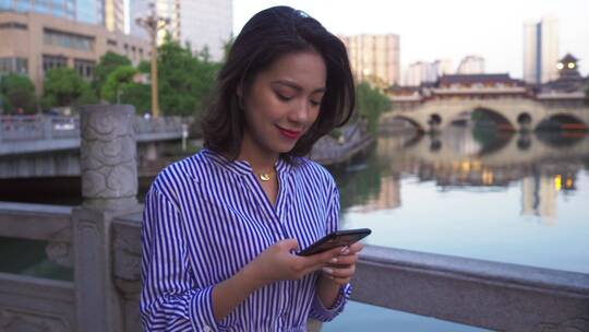 都市女青年走在成都廊桥河边看手机
