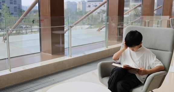 中国小男孩在图书馆大厅看书阅读
