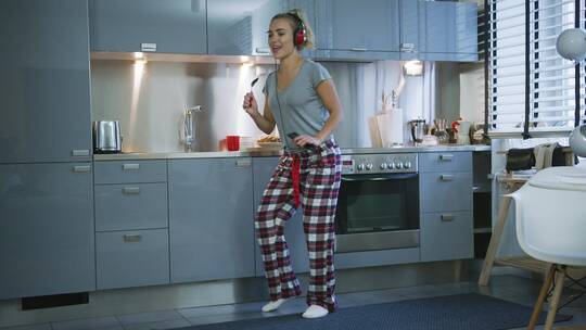 女人戴耳机在厨房里唱歌跳舞视频素材模板下载