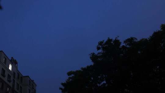 雨夜窗外的城市居民楼灯光和闪电