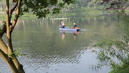 公园湖里的清洁工坐在船上清理湖水上的垃圾