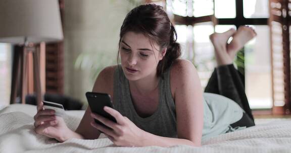 女人在卧室床上玩手机