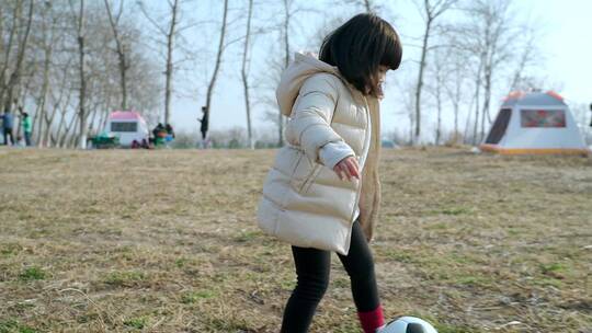 冬季在公园草坪上踢球的中国女孩视频素材模板下载