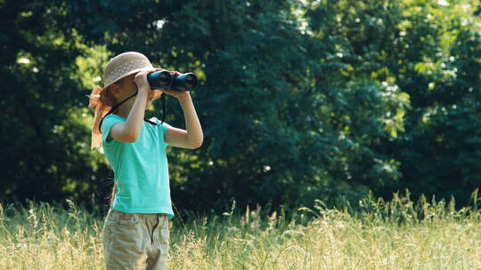孩子站在草地上拿着望远镜看动物