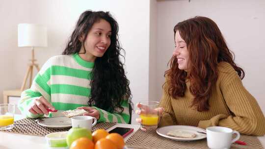 年轻的女性朋友在家里的客厅吃早餐时聊天