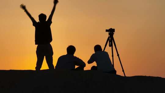 山顶上用相机记录唯美夕阳的登山者剪影