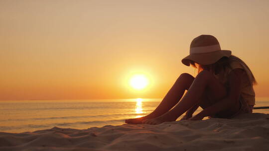 女孩坐在沙滩上看日落玩泥沙