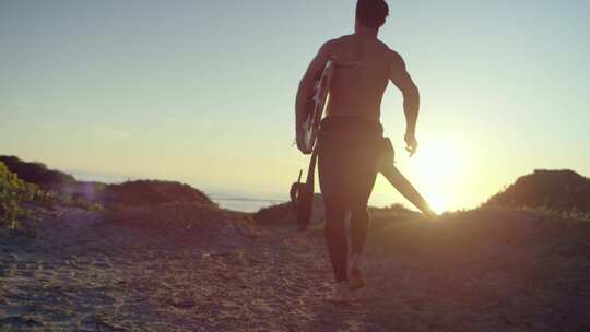 一个男人带着冲浪板跑向海滩