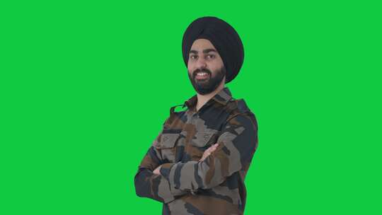 快乐的锡克教印度军人双手交叉站立的肖像绿