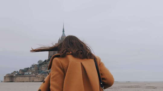 特写时尚快乐的旅游女人在史诗圣米歇尔山柔软的海沙上慢慢行走