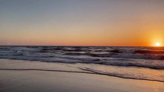 海边日落时的海浪与沙滩景色