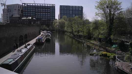 树木和城市建筑附近运河上的驳船