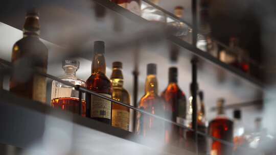 酒吧内成列的洋酒和悬挂的玻璃红酒杯