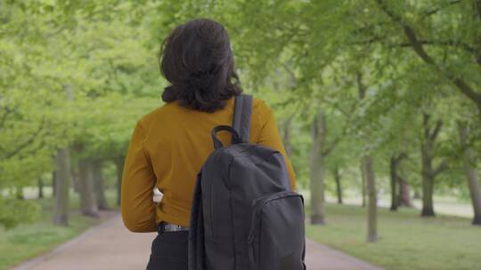 女学生走过林荫小路的跟踪镜头