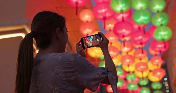 女人晚上用中国灯笼在手机上拍照