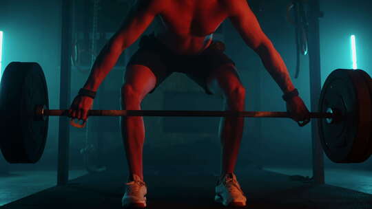 蓝光霓虹灯下的男性举重运动员正在健身房准