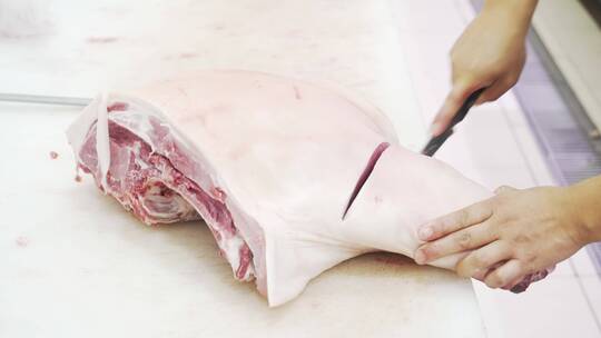 现代商超生鲜工作人员切割猪肉