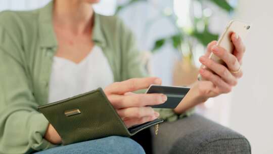 女性手持手机与信用卡