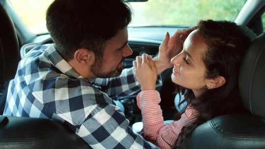 年轻夫妇面对面坐在车里等待亲吻慢动作
