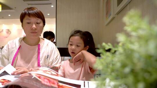 认真看着菜谱点菜的中国女孩和母亲