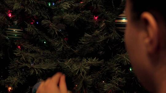 男人把装饰品挂在圣诞树上