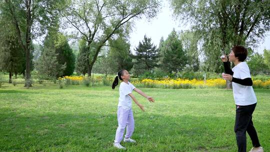 在草坪上玩吹泡泡游戏的东方母女