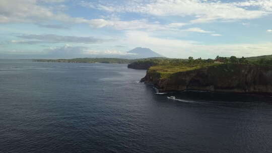 空中：巴厘岛高大岩石热带悬崖下的旅游船巡游点