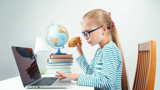 女孩边吃牛角包边玩笔记本电脑
