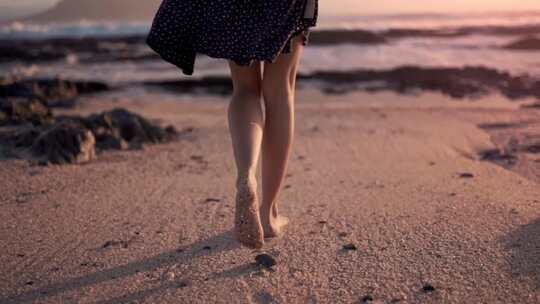 女生夕阳时在沙滩上走路散步腿部特写