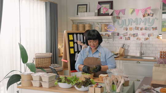 亚洲女性在云厨房做饭，管理在线送餐业务