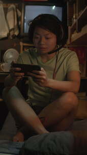亚洲微型公寓居民在智能手机上玩电子游戏
