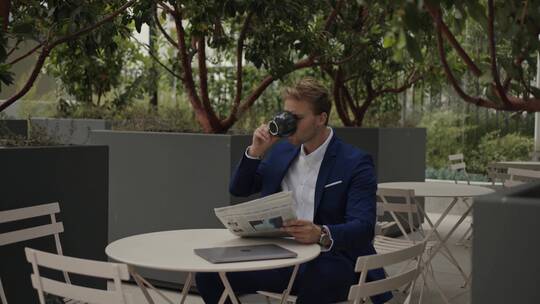 商人坐在户外边看报纸边喝咖啡视频素材模板下载