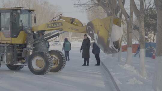 装载机铲雪作业，工作人员现场查看