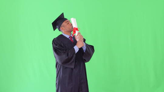 穿着毕业礼服的男子亲吻毕业证书