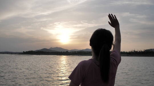 夕阳下中国女性运动后在河边喝水