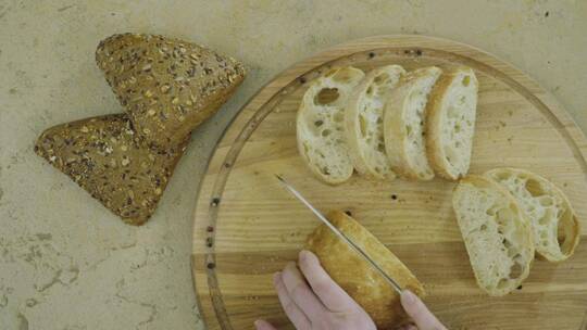 手在木板上切割新鲜面包的俯视图