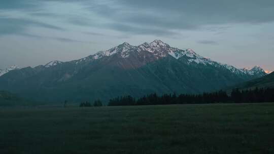 日落时，雪山靠近田野，从一辆行驶的汽车上