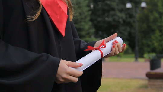 身着学位服的年轻女子手持文凭，享受毕业典