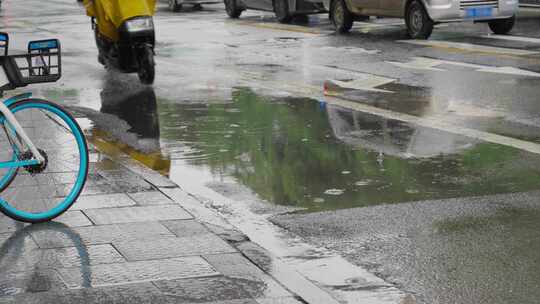 下雨天电动车路过街道积水溅起水花慢镜头