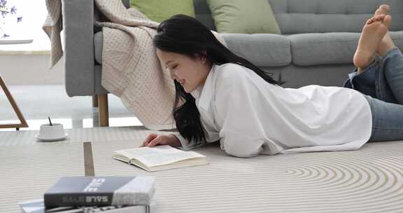 年轻女性在地毯上趴着看书