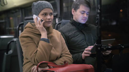公交车上使用手机和平板电脑的男人女人