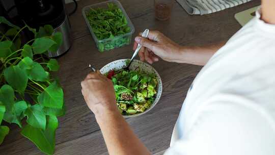 男人在家庭厨房用手混合沙拉和番茄蔬菜和绿