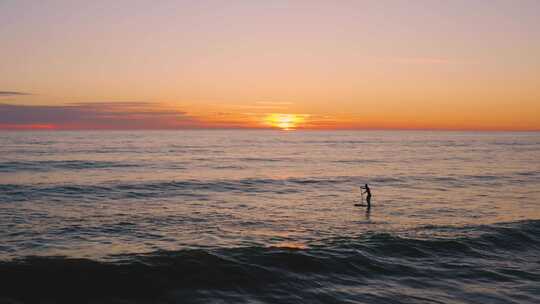 日落时划着冲浪板的人