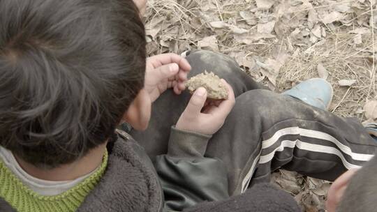 小男孩手里的土块