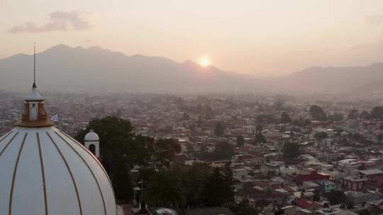 日落时分，无人机经过瓜达卢佩教堂，倾斜着，展示了圣克里斯托瓦尔德市