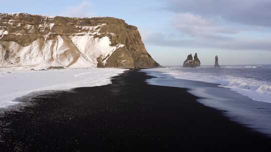 冰雪覆盖的冰岛南部黑沙滩上空的低空飞行