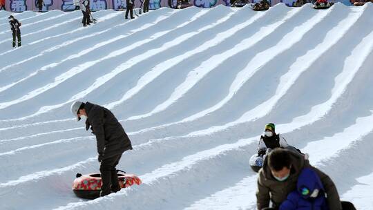 4K升格实拍冬季在冰雪乐园玩雪圈滑梯的游人视频素材模板下载